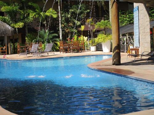 una gran piscina con sillas y mesas en Ilha flat hotel suíte Swaenen, en Ilhabela