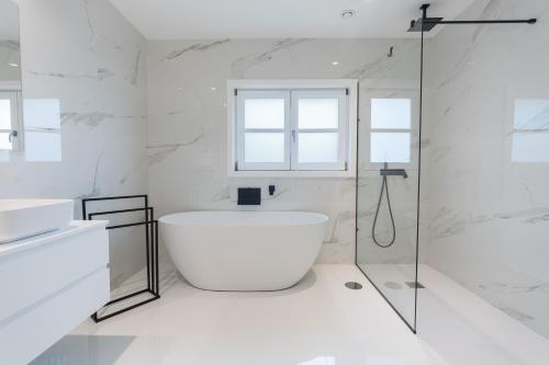 La salle de bains blanche est pourvue d'une baignoire et d'une douche. dans l'établissement Quinta Devesa do Monte, à Amares