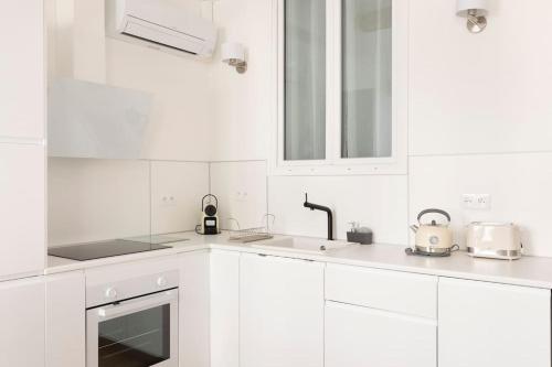 une cuisine blanche avec des armoires blanches et un évier dans l'établissement 2chambres 2 salles de bains Palais des Festivals, à Cannes