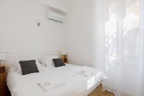 un lit blanc dans une chambre avec une fenêtre dans l'établissement 2chambres 2 salles de bains Palais des Festivals, à Cannes