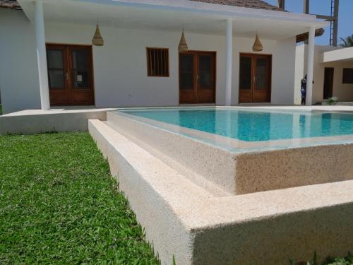 a swimming pool in front of a house at la maison de la fontaine in Cap Skirring