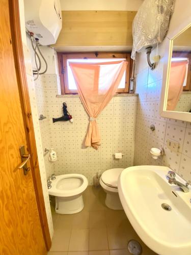 a bathroom with a toilet and a sink and a window at Un posto al sole in Fregene