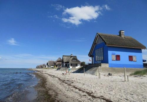 a blue house on a beach next to the water at Ferienwohnung an der Ostsee in Heiligenhafen