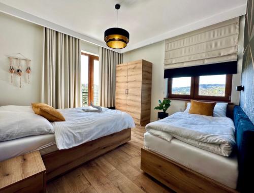 a bedroom with two beds and a large window at Apartamenty na Wyrszczku Apartament nr 3 in Istebna