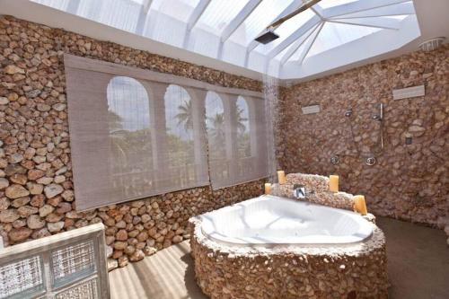 a bathroom with a large tub in a room with logs at Perfect for destination weddings & family vacations! in Arecibo