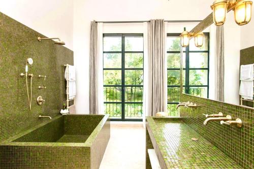 La salle de bains est pourvue d'une baignoire verte et d'une grande fenêtre. dans l'établissement La Grande Verrière - Luberon en Provence, à Goult
