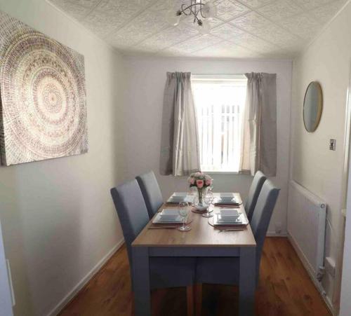 mesa de comedor con sillas azules, mesa y ventana en Spacious three bedroom house with off road parking, en Birmingham