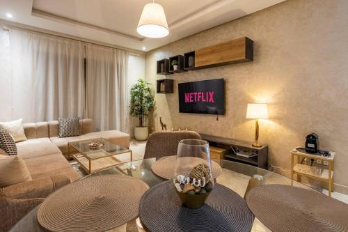 a living room with a couch and a tv at Modern Charm at Le Joyau du Parc in Mohammedia