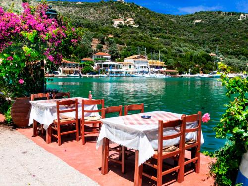 two tables and chairs sitting next to a body of water at Vlastaras Apartment in Sivota