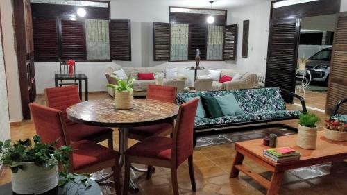 ein Wohnzimmer mit einem Sofa und einem Tisch in der Unterkunft Casarão na Praia de Camboinha a 250 metros do mar in Cabedelo