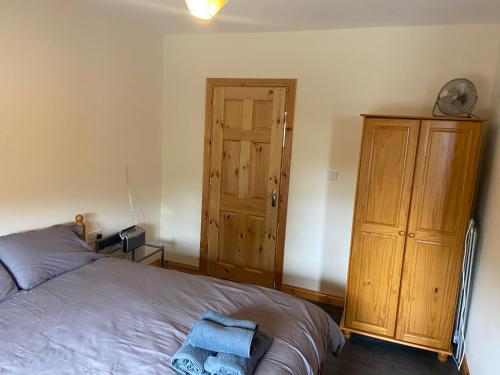 a bedroom with a bed and a wooden cabinet at Higgins House in Ballyhaunis