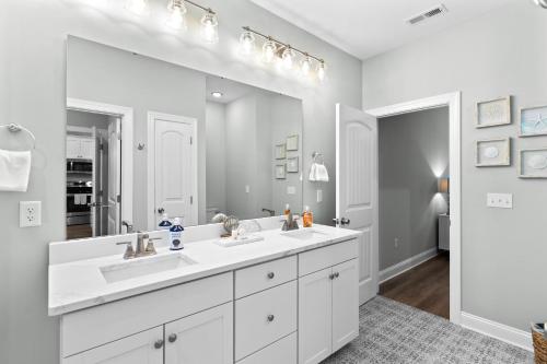 a white bathroom with two sinks and a large mirror at Ferry House - Upper Unit in Supply