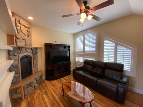 a living room with a black leather couch and a fireplace at Salmon River View in Pulaski