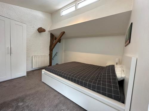 um quarto com uma cama num quarto branco em T4 Cosy dans ferme rénovée à 2 minutes de Genève em Collonges-sous-Salève