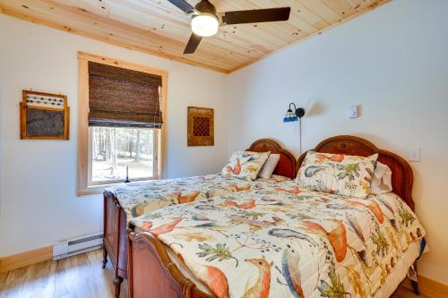 a bedroom with a bed with a comforter and a window at Beautiful Greig Cabin 2 Mi to Brantingham! in Glenfield