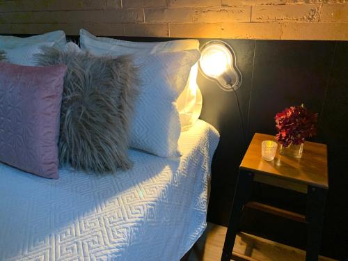 a bed with pillows and a table with a lamp at Modernidade e conforto para sua hospedagem !!! in Sao Paulo