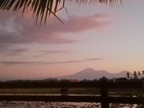 a sunset with mountains in the background at Pondok Cap Oleng Guesthouse Canggu by Ecommerceloka in Canggu