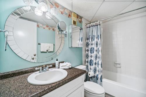 ein Badezimmer mit einem Waschbecken, einem WC und einem Spiegel in der Unterkunft Moondrifter #208 by Nautical Properties in Panama City Beach