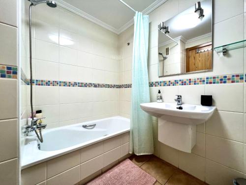 Apartment in La Tejita (El Medano) في La Tejita: حمام مع حوض وحوض استحمام ومرآة