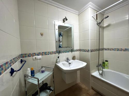 a white bathroom with a sink and a bath tub at Apartament with Garden in La Tejita