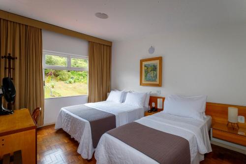 a hotel room with two beds and a window at Grande Hotel de Ouro Preto - 80 ANOS in Ouro Preto