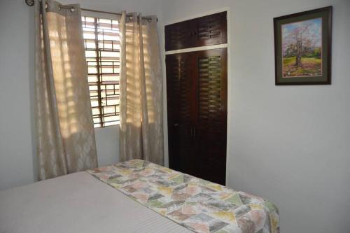 a bedroom with a bed and two windows with curtains at 1 Bedroom Upscale Apt in Kingston