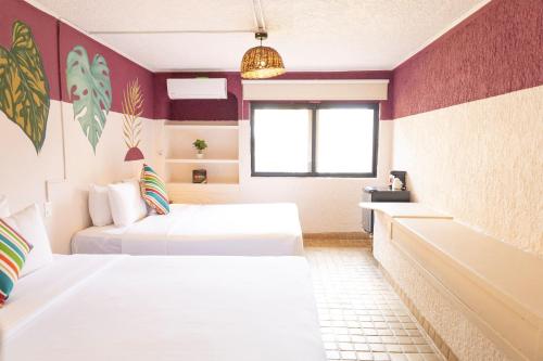 a bedroom with two beds and a tub and a window at Selina Cancun Laguna Hotel Zone in Cancún