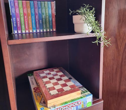 a book shelf with books and a chessboard on it at Sandy Shores Estate- Long Island in Frankston