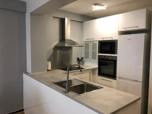 La cuisine blanche est équipée d'un évier et d'un réfrigérateur. dans l'établissement 2P cosy plein centre Antibes, à Antibes