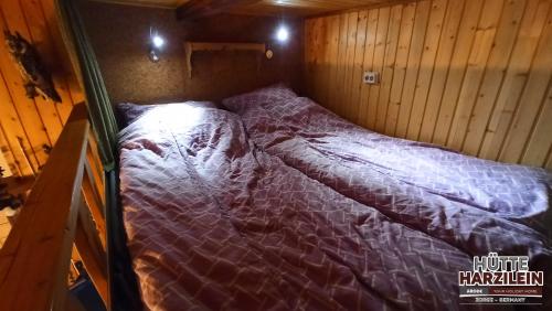 a bed in a cabin with a purple comforter at Arode Hütte Harzilein - Romantic tiny house on the edge of the forest in Zorge