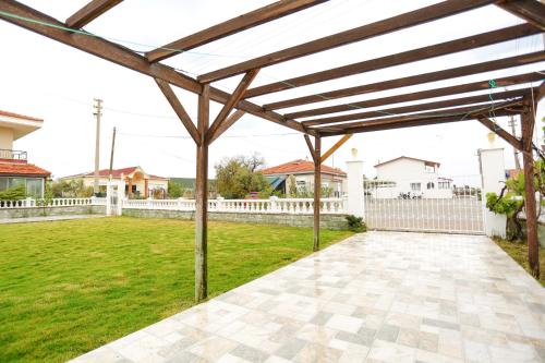 a wooden pergola in a yard with a white fence at River & Sea Villa in Cesme