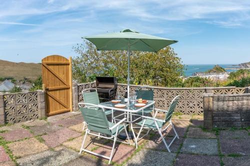 a table and two chairs with an umbrella at The Tempest, sea views, coastal & rural walks. in Ilfracombe