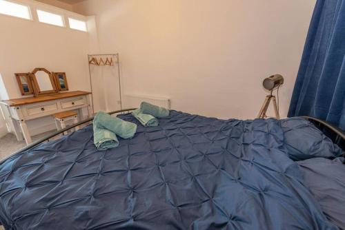 a bedroom with a blue bed with two pillows on it at The Tempest, sea views, coastal & rural walks. in Ilfracombe