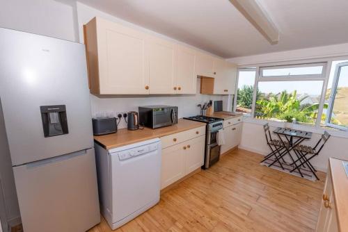 a kitchen with white appliances and a large window at The Tempest, sea views, coastal & rural walks. in Ilfracombe