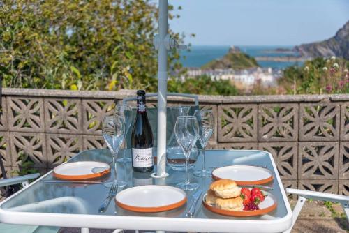 a table with a bottle of wine and a plate of food at The Tempest, sea views, coastal & rural walks. in Ilfracombe