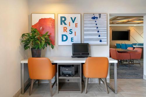 an office with a desk with a computer and orange chairs at Holiday Inn Express San Bernardino Colton by IHG in Colton