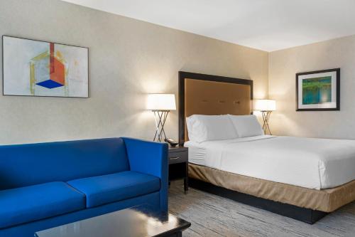 a hotel room with a bed and a blue couch at Holiday Inn Express Colton, an IHG Hotel in Colton