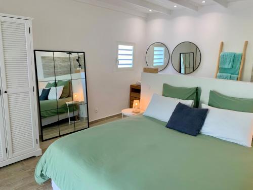 ein Schlafzimmer mit einem großen Bett und zwei Spiegeln in der Unterkunft SUNSEEKER SXM - Jardins Orient Bay - Appartement vue mer ou Studio vue Colline in Saint Martin