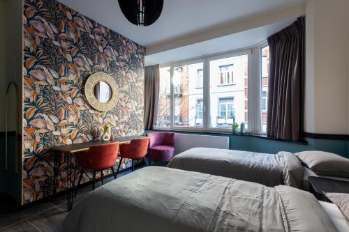 een slaapkamer met 2 bedden, een tafel en een spiegel bij Hey - Aparthotel Brussels in Brussel