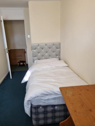 a large bed in a room with a wooden table at 6 Greville Court in London