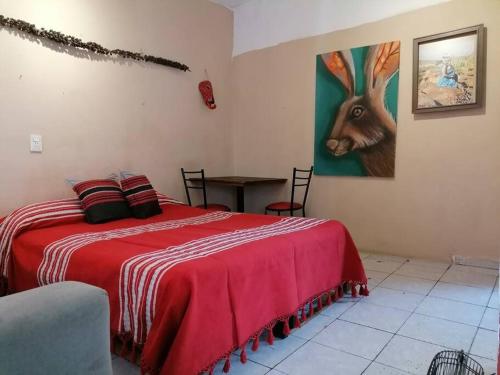 モンテレイにあるRojoMecate estudio artistico en Monterrey Ponienteの赤いベッドと鹿の絵画が備わるベッドルーム