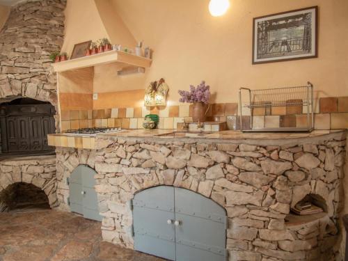 une grande cuisine en pierre avec une grande cheminée en pierre dans l'établissement La Bergerie, à Cotignac