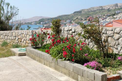 a stone retaining wall with flowers in a garden at Studio Metajna 208b in Metajna