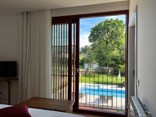 a bedroom with a sliding glass door with a view of a pool at Quinta de Chousas - Braga - Agroturismo in Braga