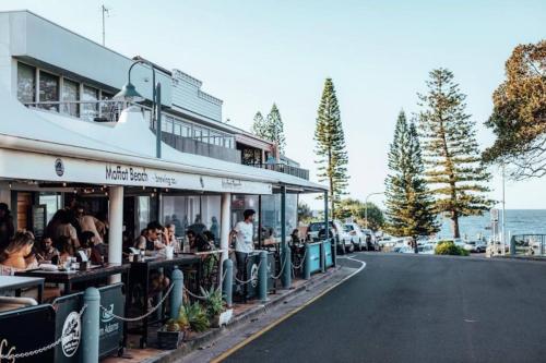 um restaurante com pessoas sentadas em mesas ao lado de uma estrada em Beach House @ Moffat em Caloundra