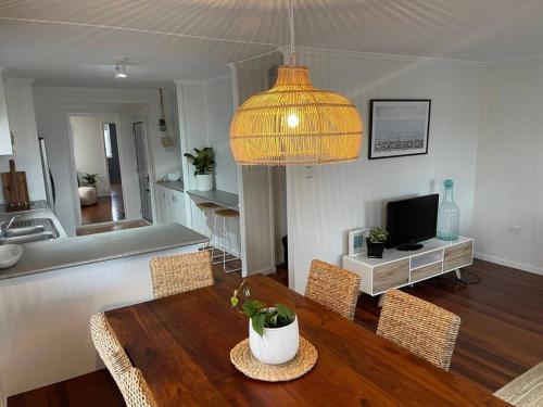 uma sala de estar com uma mesa e cadeiras e uma televisão em Beach House @ Moffat em Caloundra