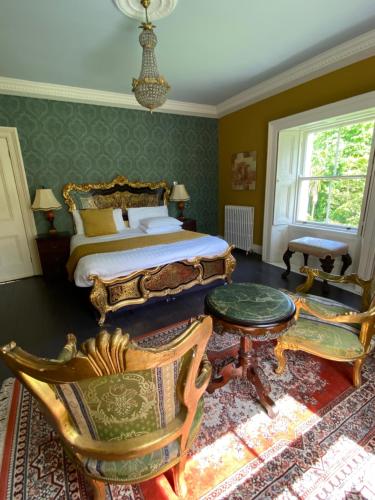 a bedroom with a bed and a table and chairs at Clone Country House in Aughrim