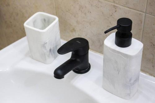 a bathroom sink with a black faucet and a container at Exclusive on Rio Negro in Montevideo