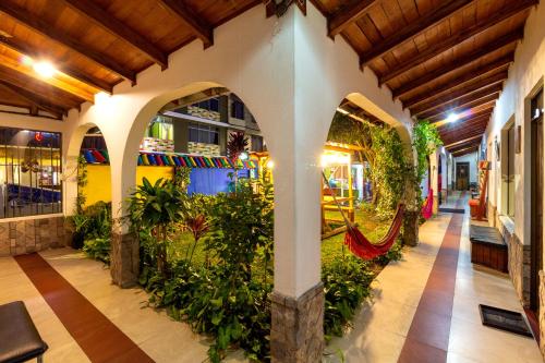 an indoor garden in a building with arches and plants at Santa Cruz Backpackers Hostal in Baños