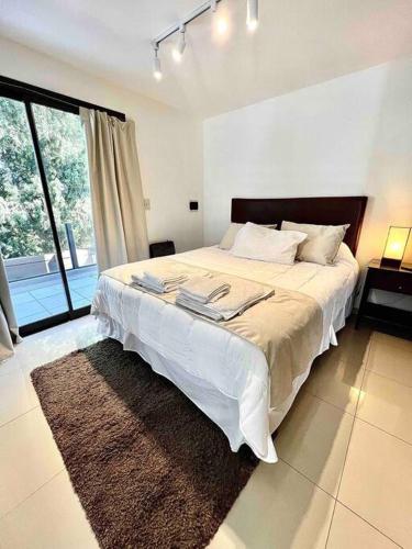 a bedroom with a large bed and a large window at Hermoso Departamento en Barrio Jardin in Cordoba